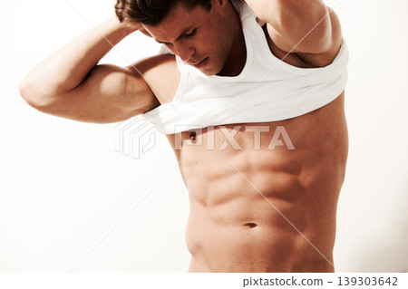 Man, dressing and model with shirt in studio, white background and bodybuilder with abs and stomach. Change, tshirt and person with clothes, fashion or confidence in muscular body with chest muscles Man, dressing and model with shirt in studio, white background and bodybuilder with abs and stomach. Change, tshirt and person with clothes, fashion or confidence in muscular body with chest muscles 139303642