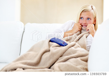 Horror, fear and woman on sofa watching tv with remote, blanket and streaming movies in home. Terror, television and girl on couch in living room with shock for scary video, film or network show. Horror, fear and woman on sofa watching tv with remote, blanket and streaming movies in home. Terror, television and girl on couch in living room with shock for scary video, film or network show. 139303789