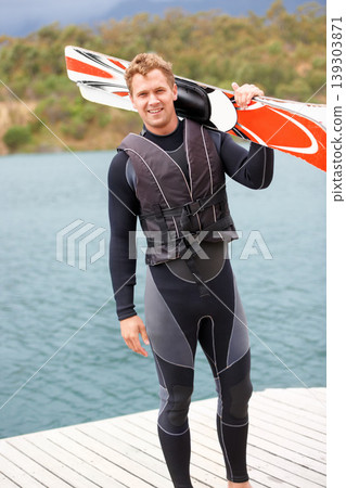Water ski, portrait and man by lake with wakeboard for surfing, exercise and recreation hobby outdoors. Fitness, extreme sports and excited person with board for skiing for freedom, adventure and fun 139303871