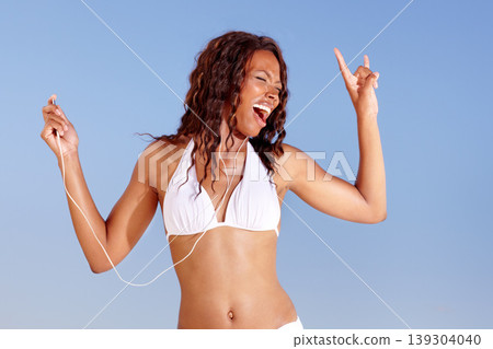 Black woman, dancing and bikini with holiday and music from happy audio and headphones in studio. Smile, singing and travel with freedom and vacation of African female person with blue background 139304040