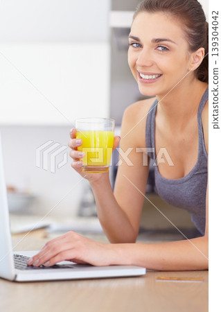 Portrait, laptop and smile for orange juice with a woman in the kitchen of her home to relax in the morning. Computer, online shopping and a happy young person in the apartment for ecommerce payment 139304042