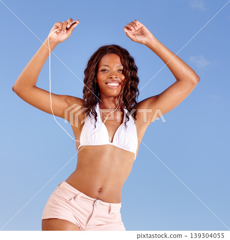 Black woman, dancing and bikini portrait with holiday and travel from happy audio and headphones in studio. Smile and music with freedom and vacation of African female person with blue background Black woman, dancing and bikini portrait with holiday and travel from happy audio and headphones in studio. Smile and music with freedom and vacation of African female person with blue background 139304055