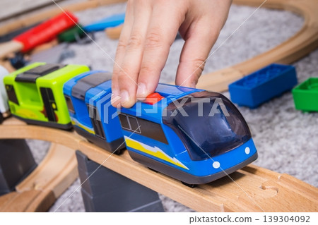 Hand of boy playing with train and wooden toy tracks. Child development and happy childhood Hand of boy playing with train and wooden toy tracks. Child development and happy childhood 139304092