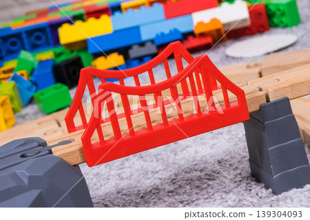 Bridge with wooden toy tracks and plastic bricks for play of children Bridge with wooden toy tracks and plastic bricks for play of children 139304093