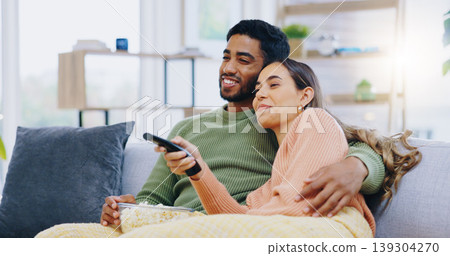 Couple, watching tv and popcorn on living room sofa for smile, hug or relax with remote for choice, show or film. Man, woman and happy together for embrace, movie or streaming on lounge couch in home Couple, watching tv and popcorn on living room sofa for smile, hug or relax with remote for choice, show or film. Man, woman and happy together for embrace, movie or streaming on lounge couch in home 139304270