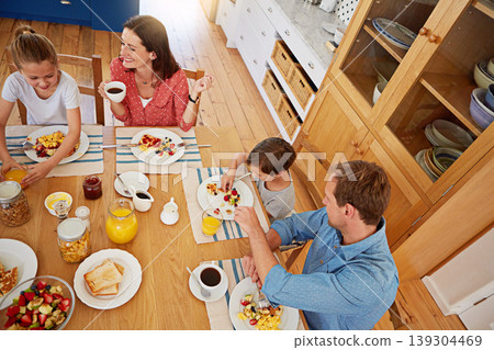 Above, breakfast and morning with a family in the dining room of their home together for health or nutrition. Mother, father and children eating food at a table in their apartment for love or bonding Above, breakfast and morning with a family in the dining room of their home together for health or nutrition. Mother, father and children eating food at a table in their apartment for love or bonding 139304469