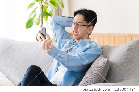 A man looks at his smartphone in surprise and panic. 139304484