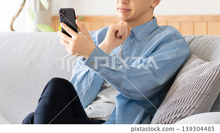 一名表情嚴肅的男子正看著他的智慧型手機，陷入沉思。 139304485