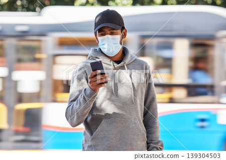 Man in city with mask, phone and travel in morning at bus stop, checking service schedule or social media. Public transport safety in covid, urban commute and person in street with smartphone app. 139304503