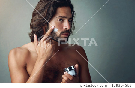 Portrait, skincare or lotion with a shirtless man in studio on a gray background for his grooming routine. Beauty, facial and and the body of a handsome young person with antiaging cream for his skin 139304595