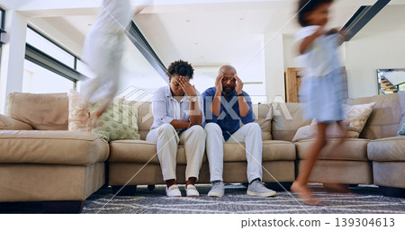 Parents, stress and headache from children in home with noise, energy or overwhelmed in living room. Hyper active, adhd and tired mother and father with burnout from kids running, games or chaos 139304613
