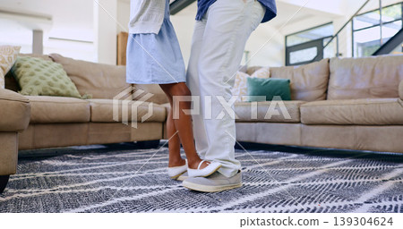 Father, daughter and feet with dancing in living room for love, relax and bonding with music and movement. Black family, man or girl child with having fun, dancer and teaching steps in lounge of home 139304624