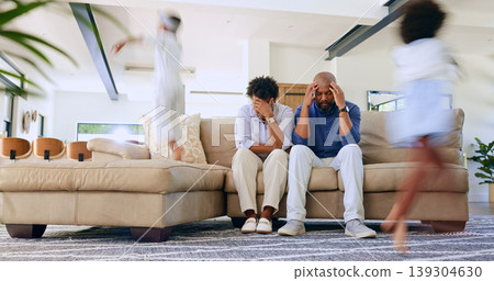 Children running and parents on sofa with stress, headache or burnout in the living room at home. Upset, mad and African mother and father with migraine for kids playing and having fun in lounge. Children running and parents on sofa with stress, headache or burnout in the living room at home. Upset, mad and African mother and father with migraine for kids playing and having fun in lounge. 139304630