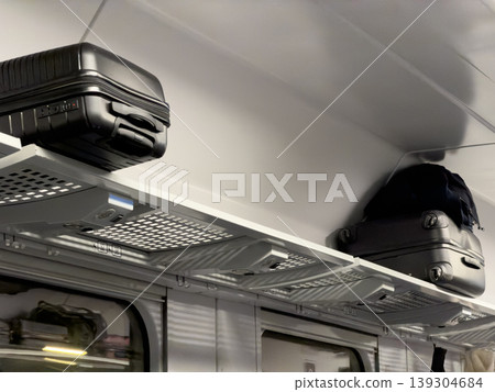 Modern luggage rests on overhead storage rack inside a train compartment, enabling efficient travel and organized journey Modern luggage rests on overhead storage rack inside a train compartment, enabling efficient travel and organized journey 139304684