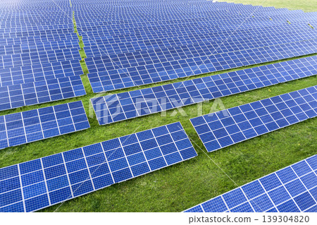 Large field of solar photo voltaic panels system producing renewable clean energy on green grass background. 139304820