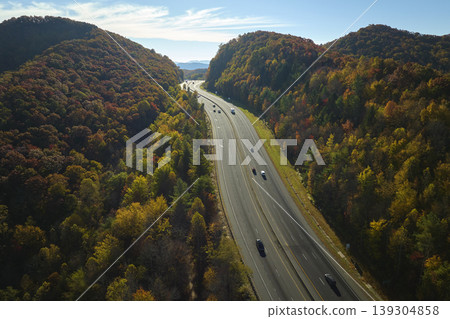 I-40 freeway road leading to Asheville in North Carolina thru Appalachian mountains with yellow fall forest and fast moving trucks and cars. Concept of high speed interstate transportation I-40 freeway road leading to Asheville in North Carolina thru Appalachian mountains with yellow fall forest and fast moving trucks and cars. Concept of high speed interstate transportation 139304858