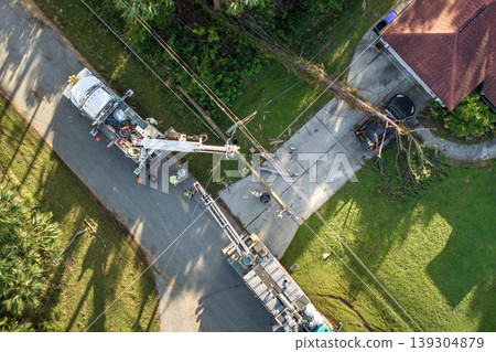 Hurricane aftermath in Florida. Workers using bucket trucks to repair blown down electrical wires at residential house. Utility services fixing damaged power lines Hurricane aftermath in Florida. Workers using bucket trucks to repair blown down electrical wires at residential house. Utility services fixing damaged power lines 139304879