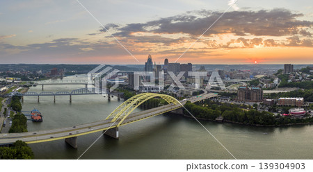 Highway traffic in Cincinnati, Ohio on Daniel Carter Beard Bridge with brightly illuminated high skyscraper buildings in downtown district. American city with business financial district at sunset Highway traffic in Cincinnati, Ohio on Daniel Carter Beard Bridge with brightly illuminated high skyscraper buildings in downtown district. American city with business financial district at sunset 139304903