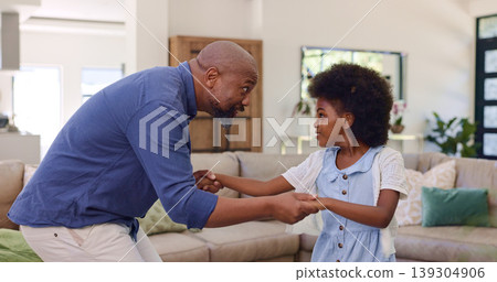 Father, daughter and dancing in living room for holding hands, relax and bonding with music and movement. Black family, man or girl child with having fun, dancer and teaching steps in lounge of house 139304906