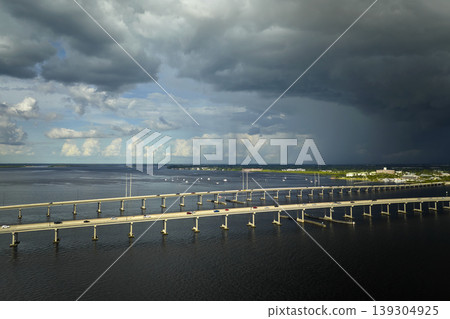 Heavy thunderstorm approaching traffic bridge connecting Punta Gorda and Port Charlotte over Peace River. Bad weather conditions for driving during rainy season in Florida 139304925
