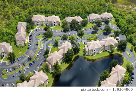 Gated residential community with condo homes in Florida with lake water in the middle. Family houses as example of real estate development in American suburbs Gated residential community with condo homes in Florida with lake water in the middle. Family houses as example of real estate development in American suburbs 139304960