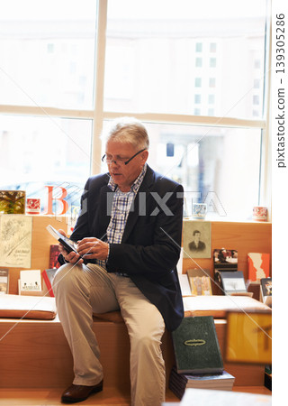 Senior man, library and author with book for literature, knowledge or story at bookstore. Mature male person, reader or bookworm reading novel, learning or wisdom in shopping choice, decision or pick 139305286