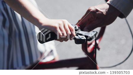 Closeup, child and teaching bicycle ride for safety, parent and neighbourhood with hands. Cycling, childhood memory and riding in summer, bonding together and handlebar with bike bell for alert 139305703