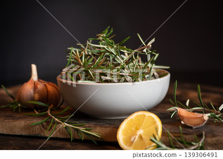Fresh Rosemary Sprigs with Garlic and Lemon on Wooden Cutting Board Fresh Rosemary Sprigs with Garlic and Lemon on Wooden Cutting Board 139306491