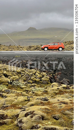 Red Car on Scenic Road Through Mossy Volcanic Landscape 139306704