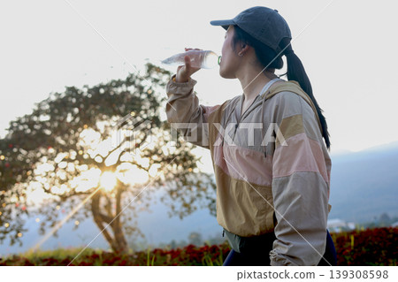 Asian women athlete drinking water from the bottle during exercise in the park 139308598