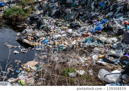 Plastic waste covers the water and ground in an urban area, creating pollution and harming the environment Plastic waste covers the water and ground in an urban area, creating pollution and harming the environment 139308839