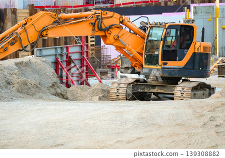 Earth moving excavator working on construction site of the building with dirt pile. Earth moving excavator working on construction site of the building with dirt pile. 139308882