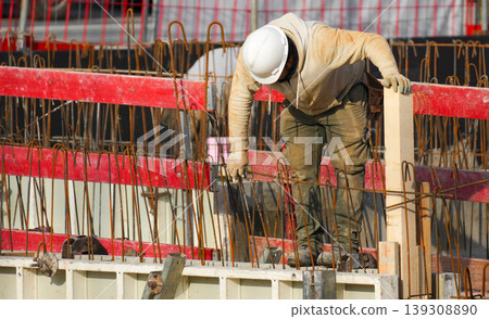 A builder works manually with tools on construction site, showing a heavy working process. A builder works manually with tools on construction site, showing a heavy working process. 139308890