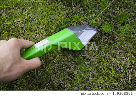 Close up of a hand releasing a spider from an insect trap over garden grass, demonstrating a responsible approach to insects. Close up of a hand releasing a spider from an insect trap over garden grass, demonstrating a responsible approach to insects. 139308891