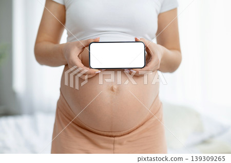 Closeup of pregnant woman holding smartphone with blank white screen 139309265