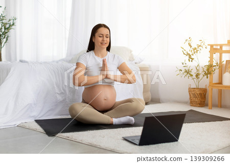 Pregnant young woman practicing yoga at home with laptop in front 139309266