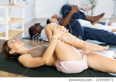 Young woman doing yoga in group in studio Young woman doing yoga in group in studio 139309471