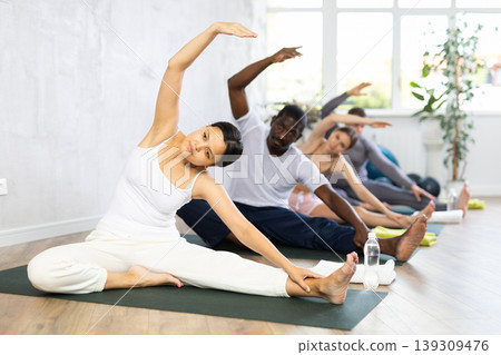 Group of people of different nationalities do stretching during yoga or pilates class Group of people of different nationalities do stretching during yoga or pilates class 139309476