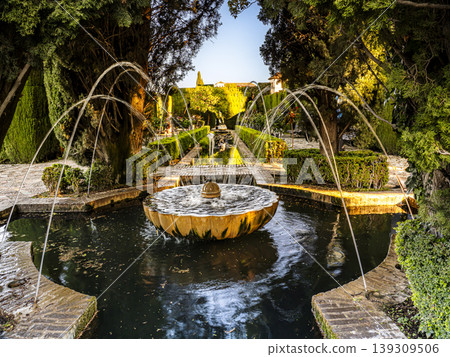 Ornate Stone Fountain in Alhambra Generalife Gardens With Arched Water Jets at Sunset, Granada Ornate Stone Fountain in Alhambra Generalife Gardens With Arched Water Jets at Sunset, Granada 139309506