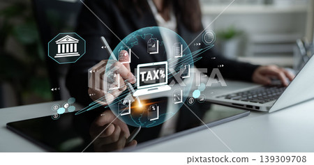 Business Professional Working on Digital Tax Preparation Concept with Financial Icons and Graphics Overlaid on a Desk with Laptop Fluxor 139309708