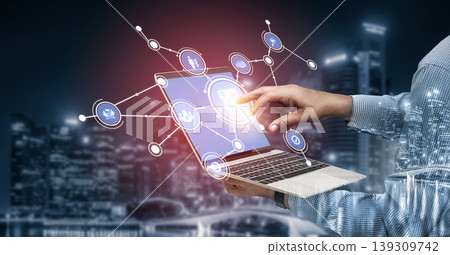 Man using laptop with virtual connections and icons, blending technology and communication in a modern urban environment, showcasing digital interaction and data flow. Tessel 139309742