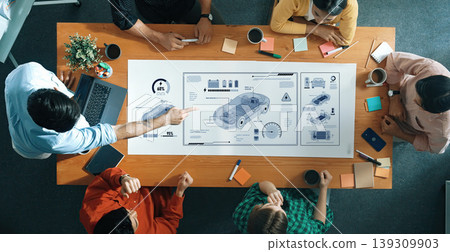 Team Collaboration in Modern Office Space for Automotive Project Development with Digital Interface and Blueprints on Table Trope 139309903