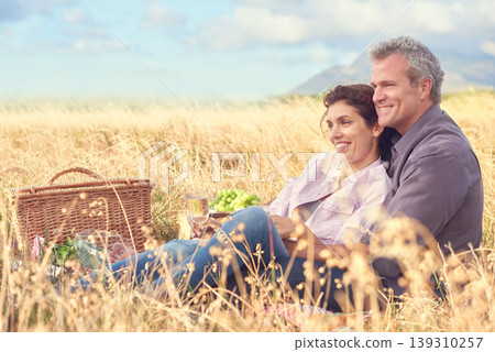 Happy, senior couple and picnic in park, grass and basket in nature for a date in retirement with love or care. Mature, woman and man in field in summer, holiday or vacation with freedom and support 139310257
