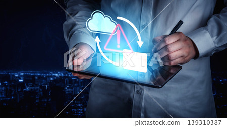 Professional man using tablet device to manage cloud data with warning sign indicating potential security risk or data transfer issue at night Gantry Professional man using tablet device to manage cloud data with warning sign indicating potential security risk or data transfer issue at night Gantry 139310387