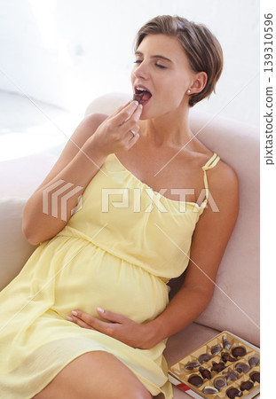 Happy woman, eating chocolate and pregnant in home, alone and enjoying delicious pregnancy craving. Good mood, comfort food and candy dessert for maternity, snack and sweet tooth satisfaction Happy woman, eating chocolate and pregnant in home, alone and enjoying delicious pregnancy craving. Good mood, comfort food and candy dessert for maternity, snack and sweet tooth satisfaction 139310596