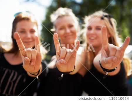 Friends, portrait and women with rocker hands at a music festival, concert of party outdoor together. Devil horns, emoji and face of female group outside for fun, celebration and rock event in a park Friends, portrait and women with rocker hands at a music festival, concert of party outdoor together. Devil horns, emoji and face of female group outside for fun, celebration and rock event in a park 139310654
