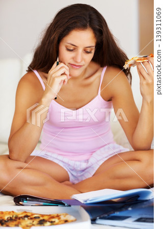 Studying, eating and woman in bedroom with pizza for dinner, lunch or supper reading documents. Paperwork, textbook and young female student enjoy fast food and preparing for test, exam or assignment 139311069