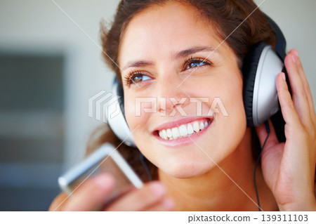 Happy, headphones and closeup of young woman listening to music, playlist or radio at home. Smile, technology and face of female person from Canada relax and streaming song or album in her apartment. Happy, headphones and closeup of young woman listening to music, playlist or radio at home. Smile, technology and face of female person from Canada relax and streaming song or album in her apartment. 139311103
