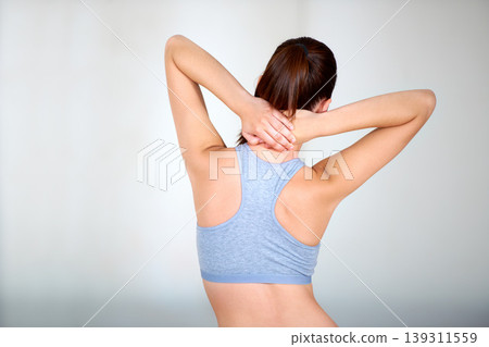 Rear view, woman and stretching in studio for exercise, workout or training with mock up space. Athlete, person and neck stretch for warm up, practice and wellbeing with sportswear on gray background 139311559