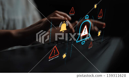 Hands on computer keyboard with floating warning symbols representing security alerts, notifications, and digital threats in a dark environment Gluon 139311628